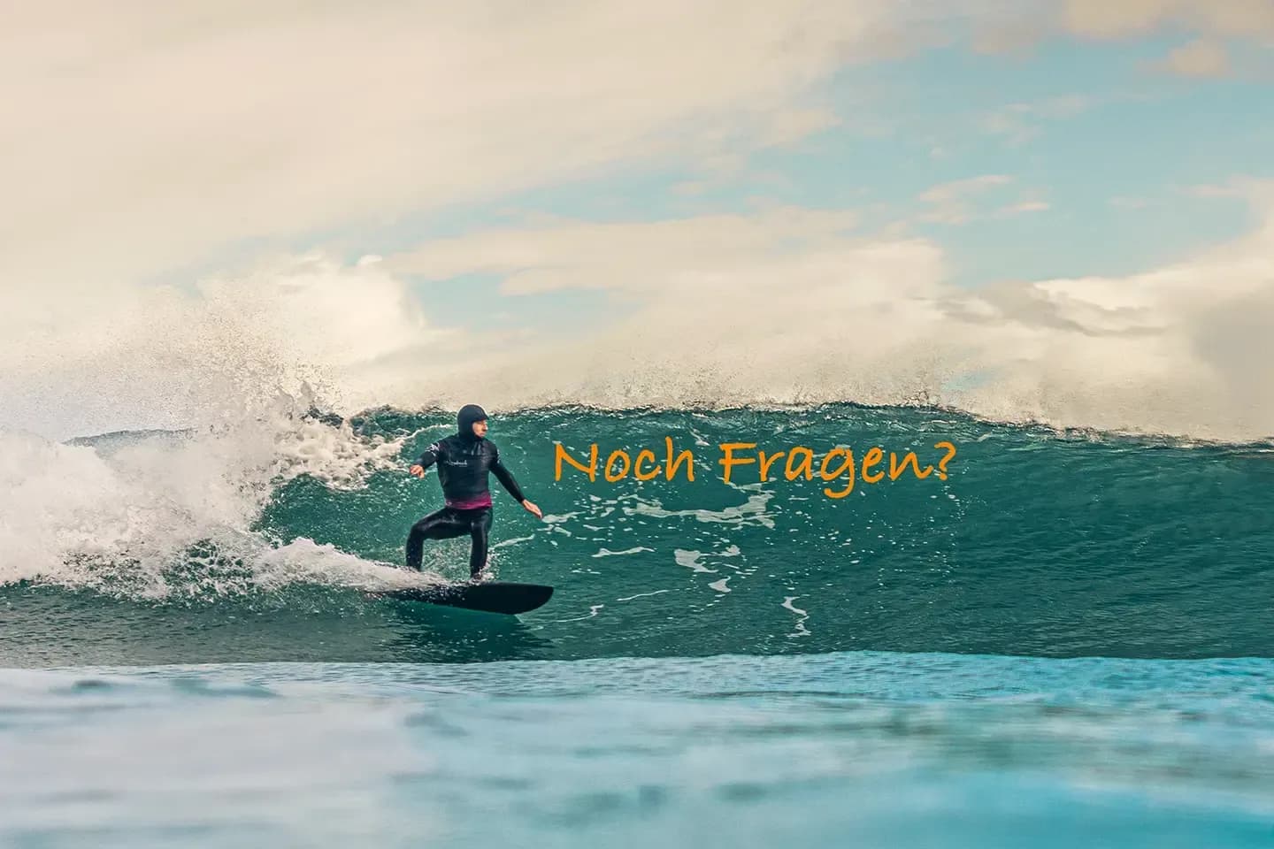 Surfer in Neoprenanzug reitet eine Welle an einem bewölkten Tag, daneben der Schriftzug „Noch Fragen?“.